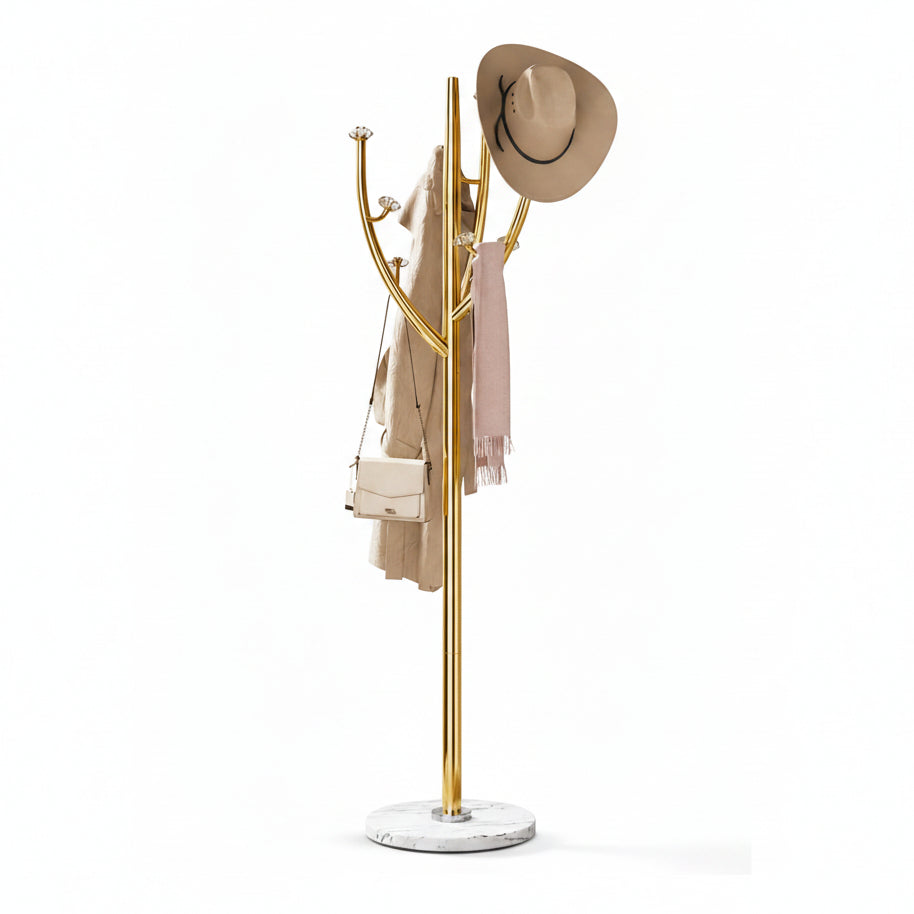 A gold metal coat rack with multiple curved hooks, displayed on a white background. It is styled with a beige wide-brim hat, a beige coat, a light pink scarf, and a small beige shoulder bag.